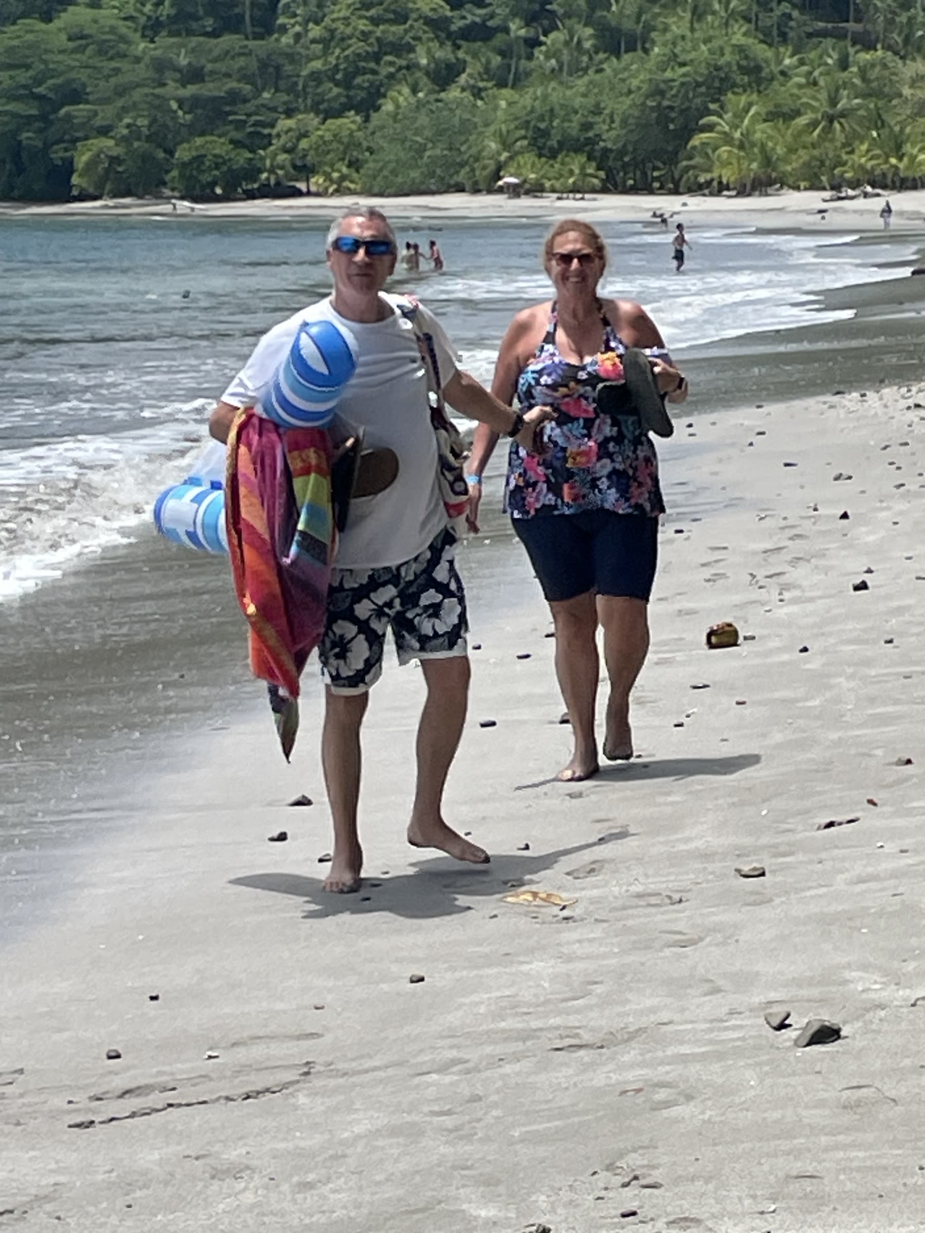 Guests walking the white-sand shoreline with their towels at Playa Mantas on a best snorkel tour Jaco beach day
