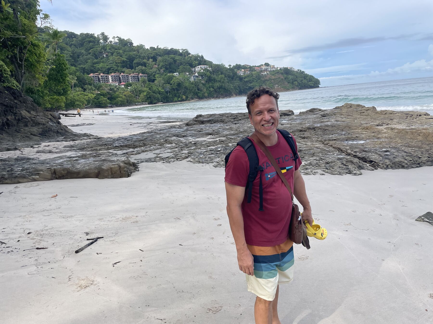 A guest walking the sand with his snorkel fins at Playa Mantas on a best snorkel tour Jaco beach day