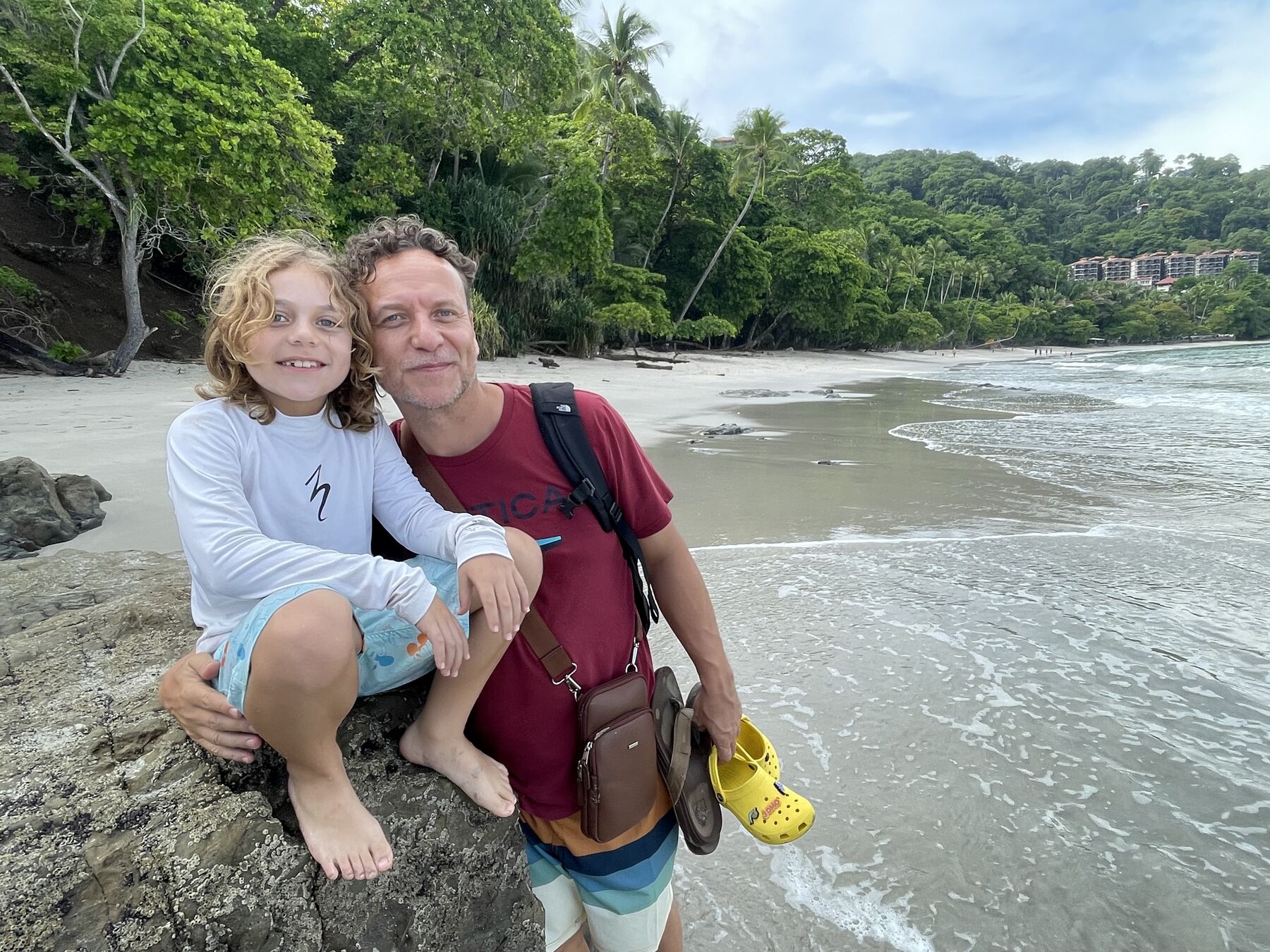 A dad and his son sitting on the rocks by the cove at Playa Mantas on a best snorkel tour Jaco beach day