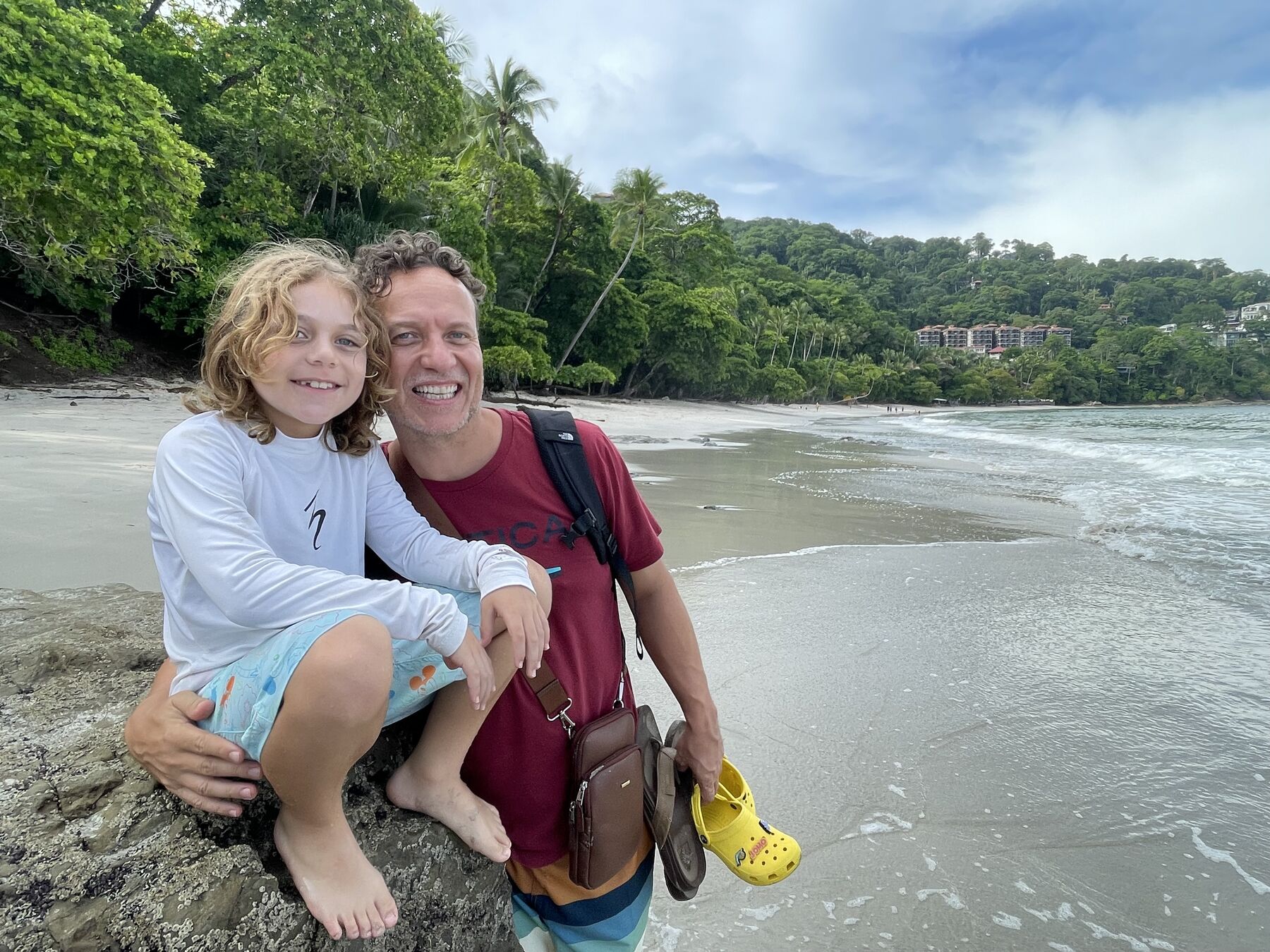 A dad and his son by the cove with the jungle behind at Playa Mantas on a best snorkel tour Jaco beach day