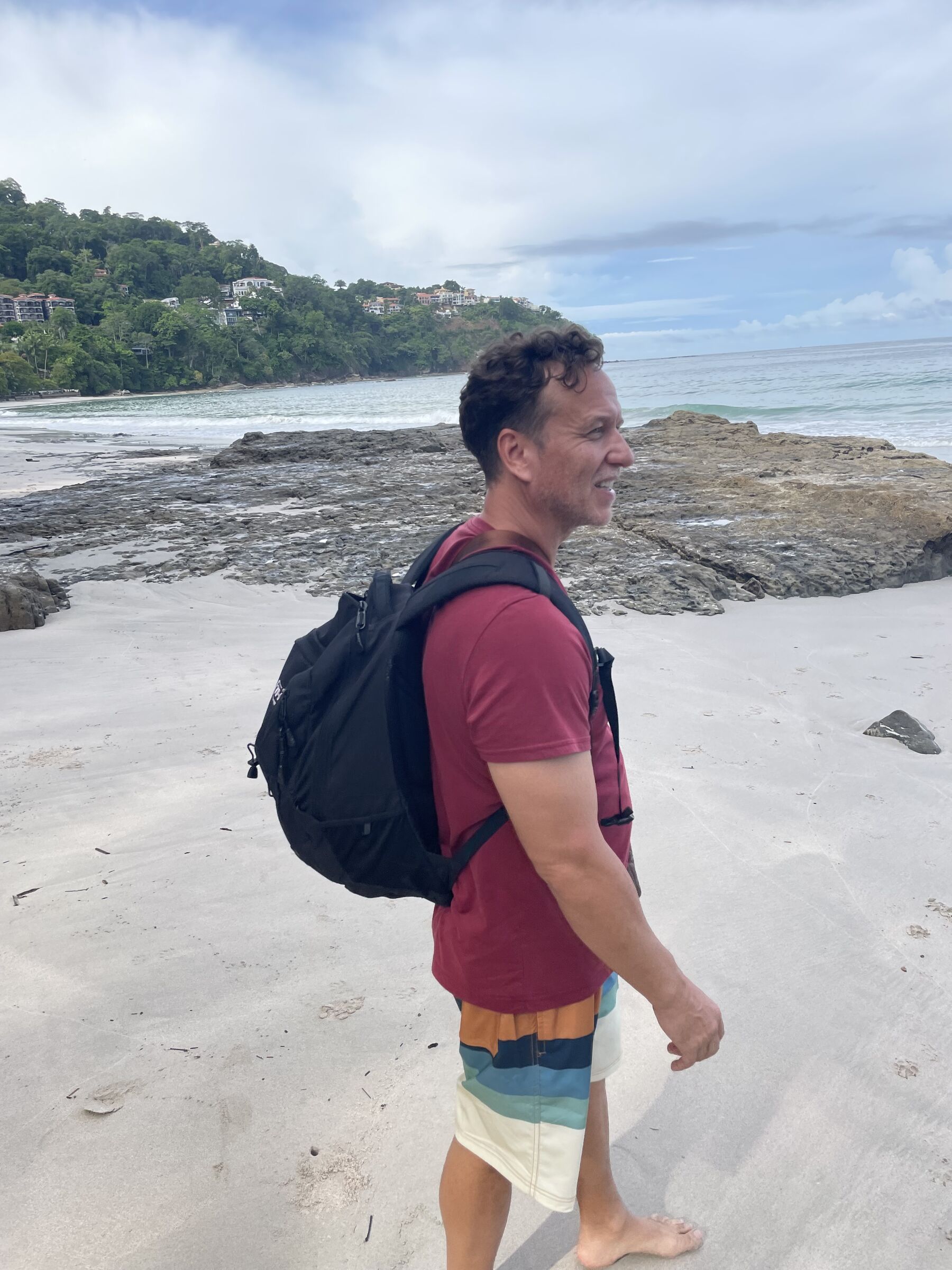 A guest on the white sand with his backpack at Playa Mantas on a best snorkel tour Jaco beach day
