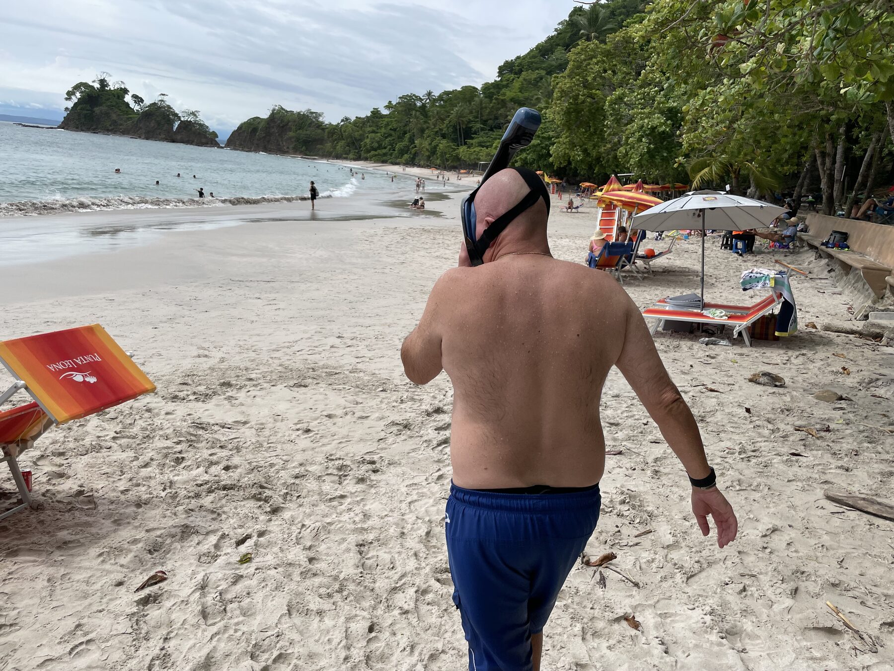 A guest wading into the clear water with snorkel gear at Playa Mantas — top snorkel tour Jaco beach