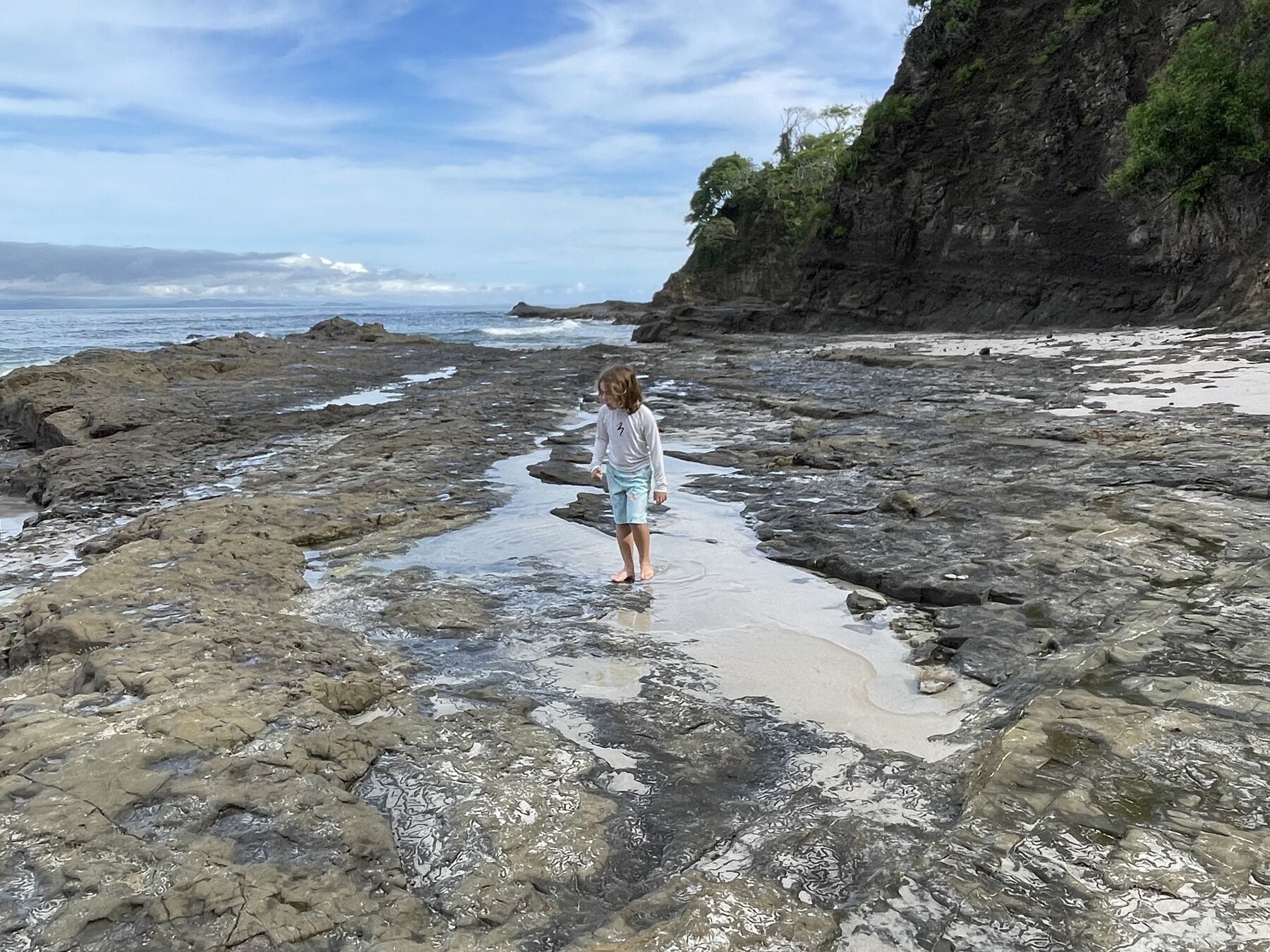 A guest walking the rocky shoreline at Playa Mantas — top snorkel tour Jaco beach
