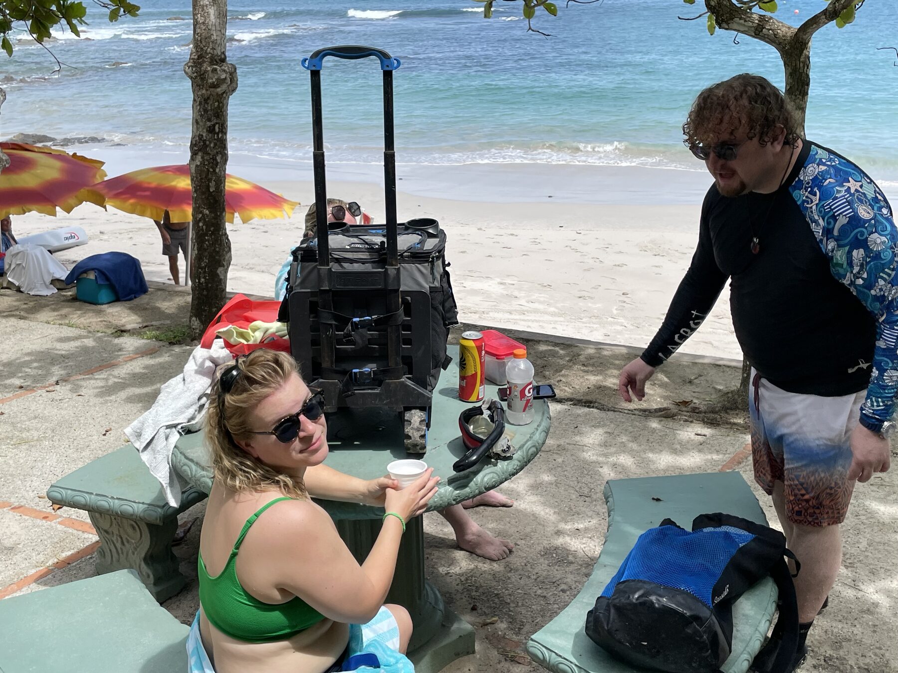 Guests relaxing with a cooler at the shaded picnic table at Playa Mantas — top snorkel tour Jaco beach