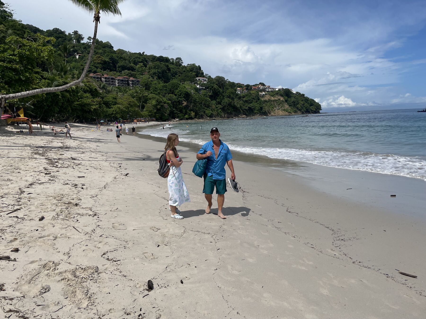 Guests strolling the sand with the wide cove and headland behind at Playa Mantas — Jaco Costa Rica best snorkeling