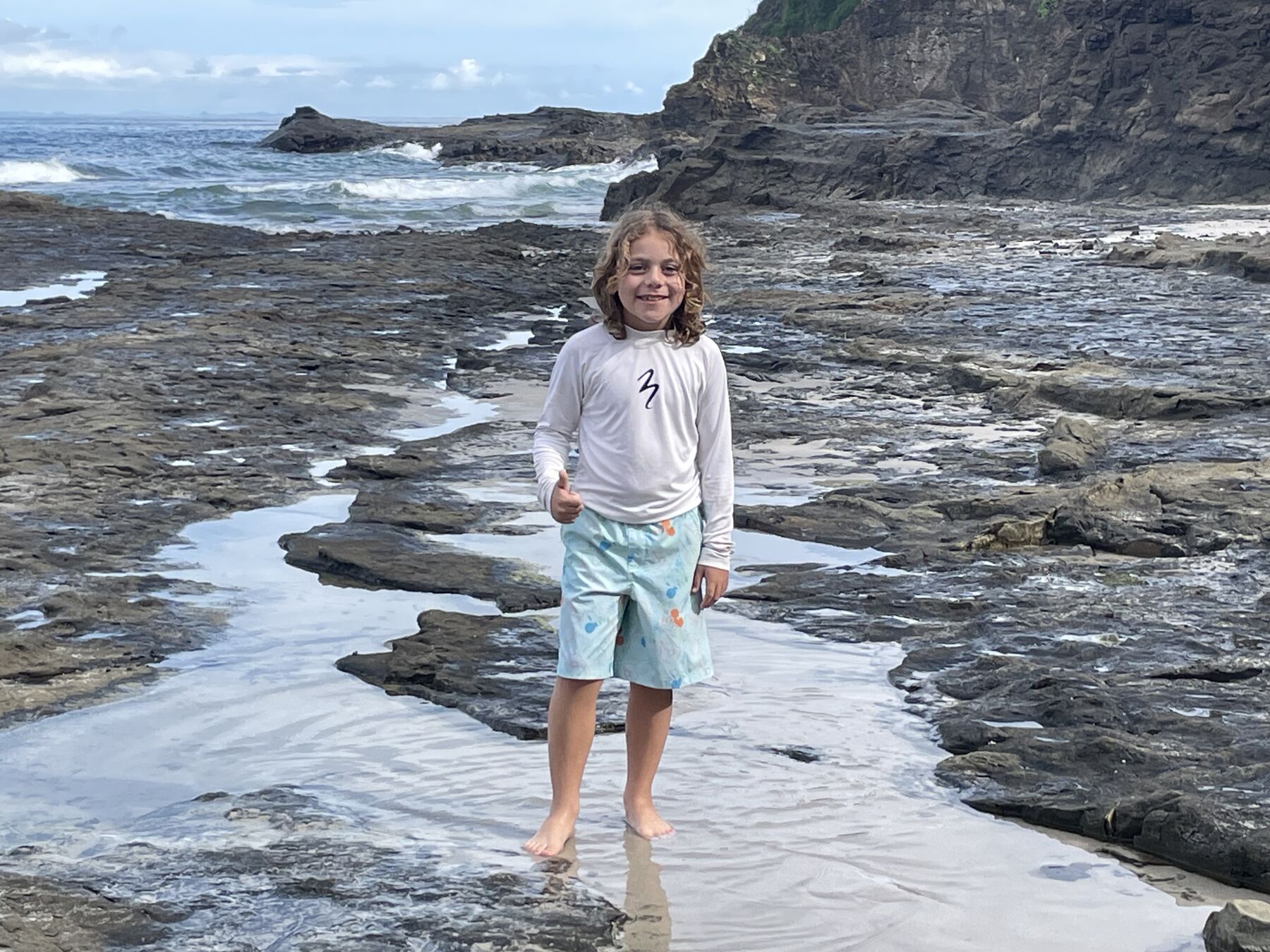 A young guest exploring the tide pools on the rocky reef at Playa Mantas on a best snorkel tour Jaco beach day
