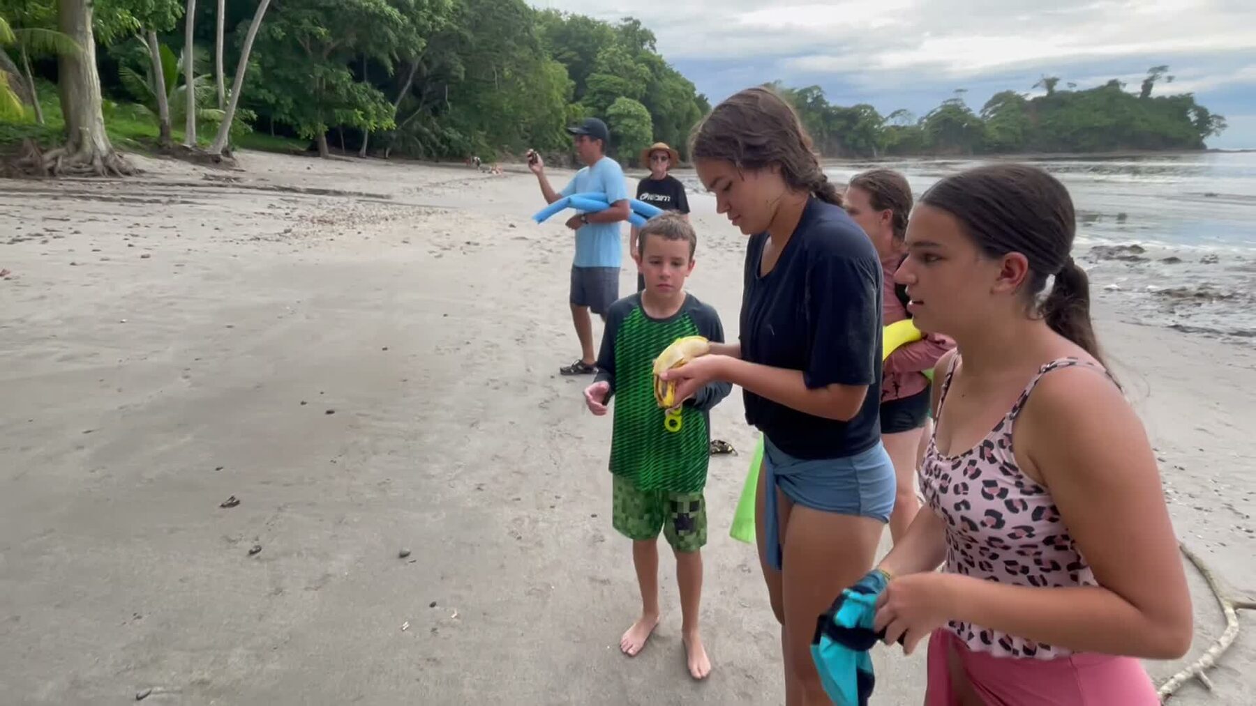 A family getting their snorkel gear ready with the guide on the sand at Playa Mantas on a best snorkel tour Jaco beach day