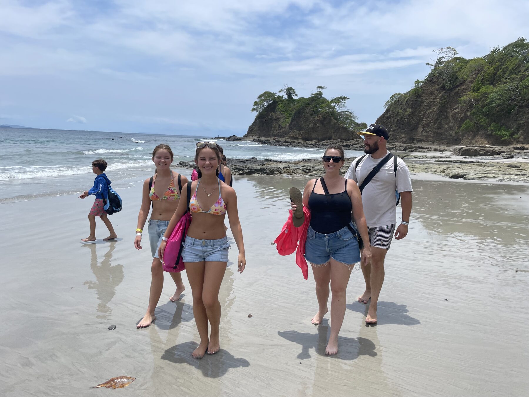 A family of snorkel tour guests on the white-sand beach near Playa Mantas, north of Jacó, Costa Rica — a great low season group booking