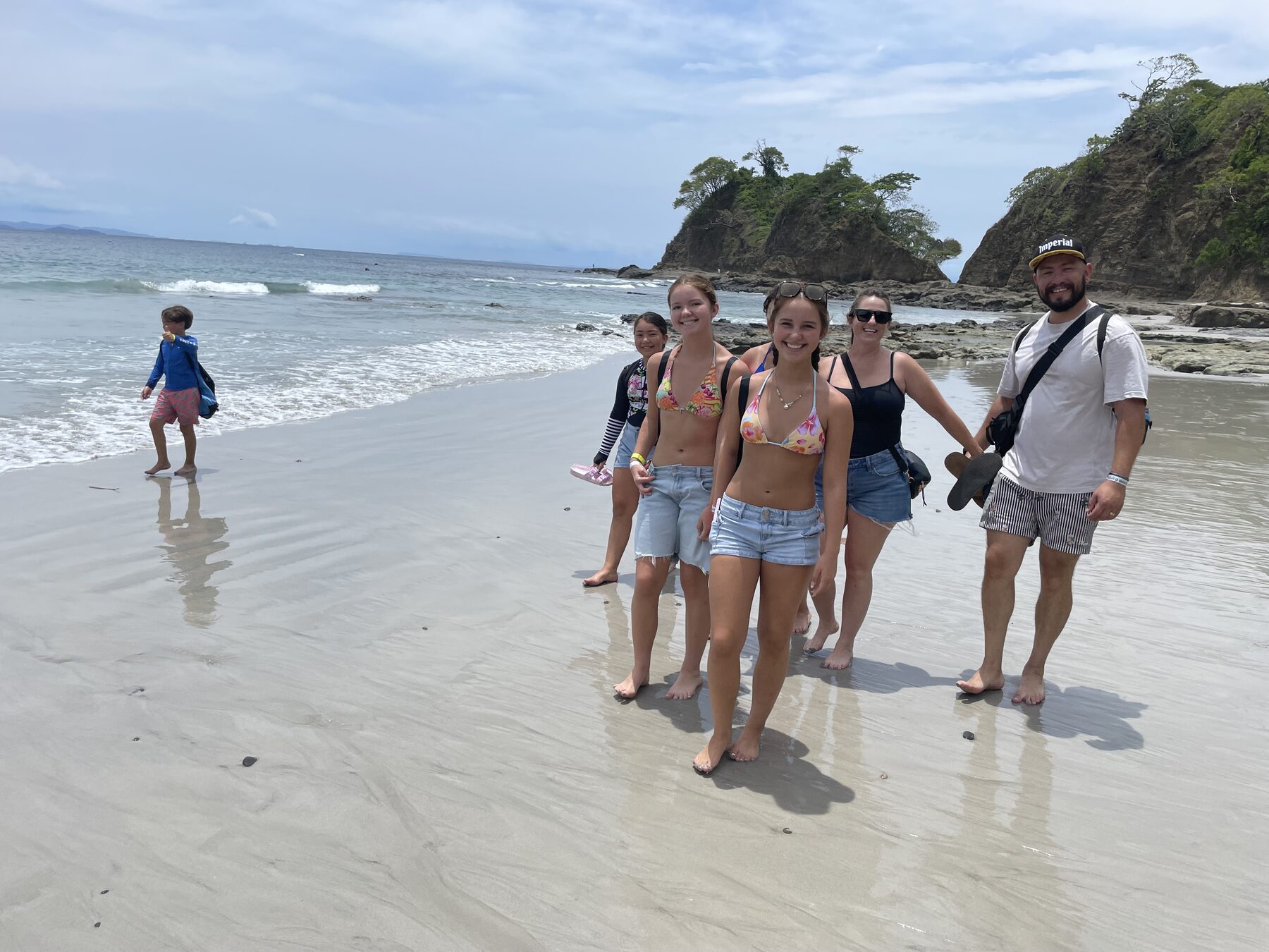 Happy group of guests walking the white-sand beach on a snorkel tour near Jacó, Costa Rica