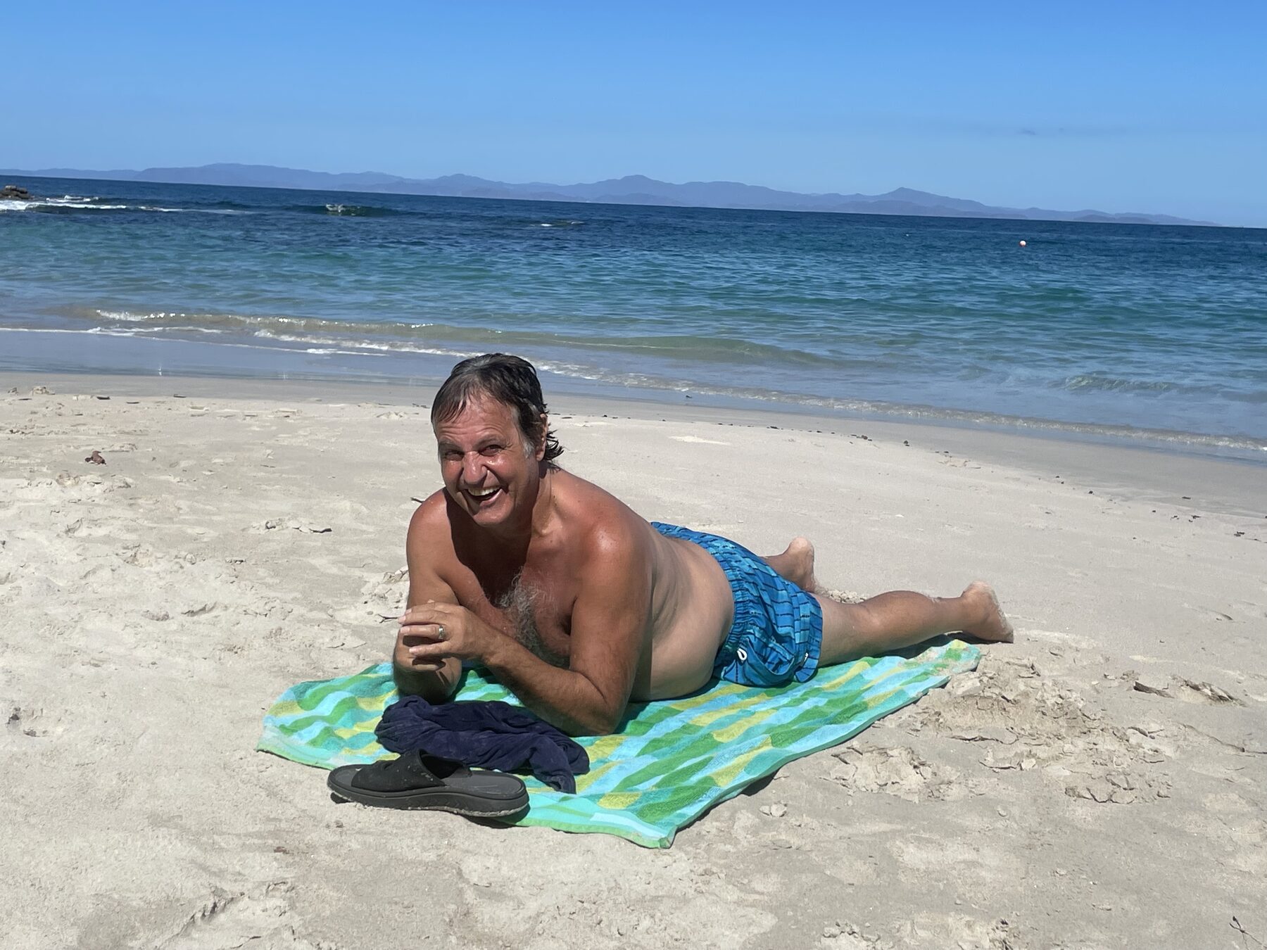 Snorkel tour guest with a towel relaxing on the beach near Jacó, Costa Rica after snorkeling