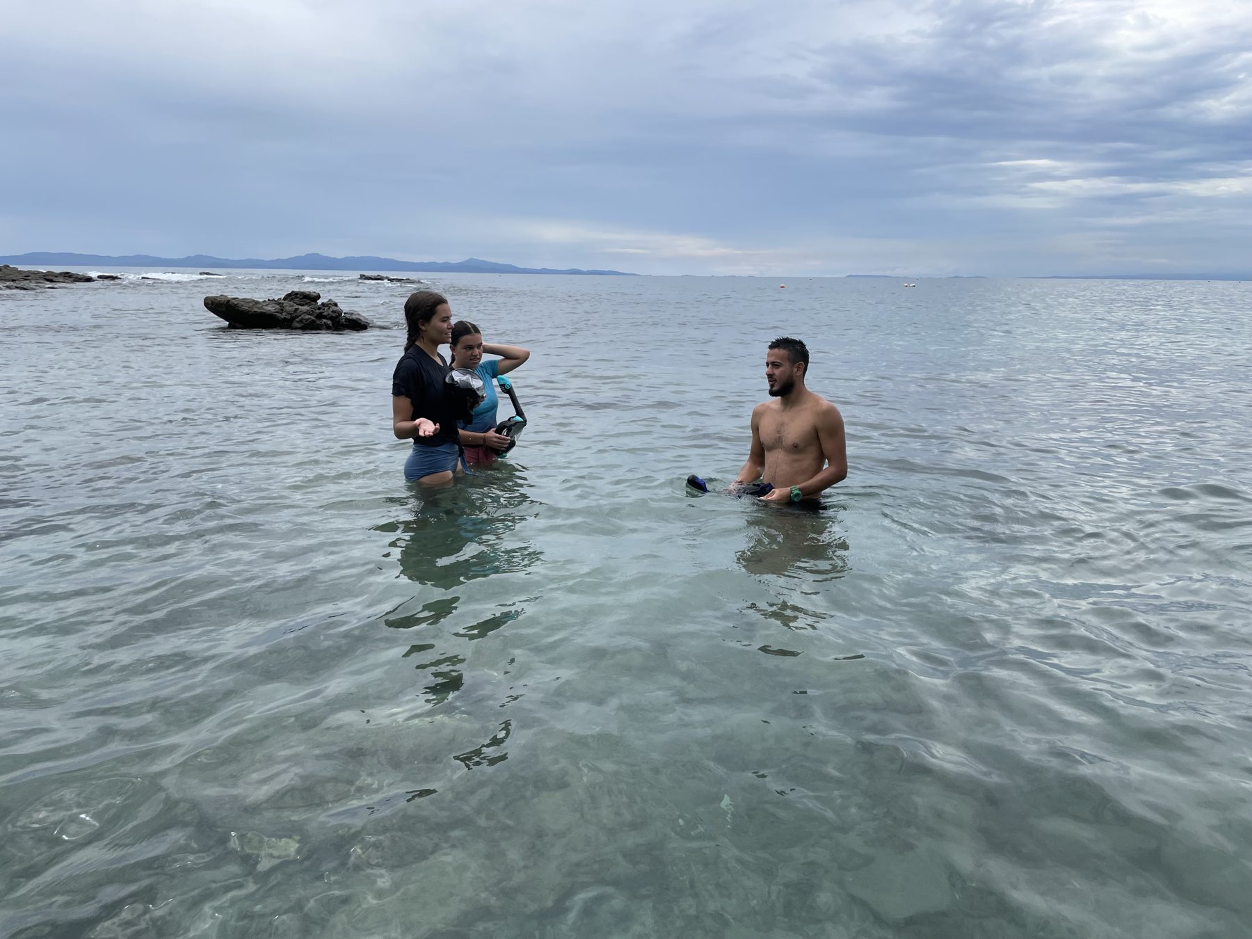 Guide walking guests into calm, clear water from the beach on the best snorkel tour Jacó Beach has for people prone to seasickness