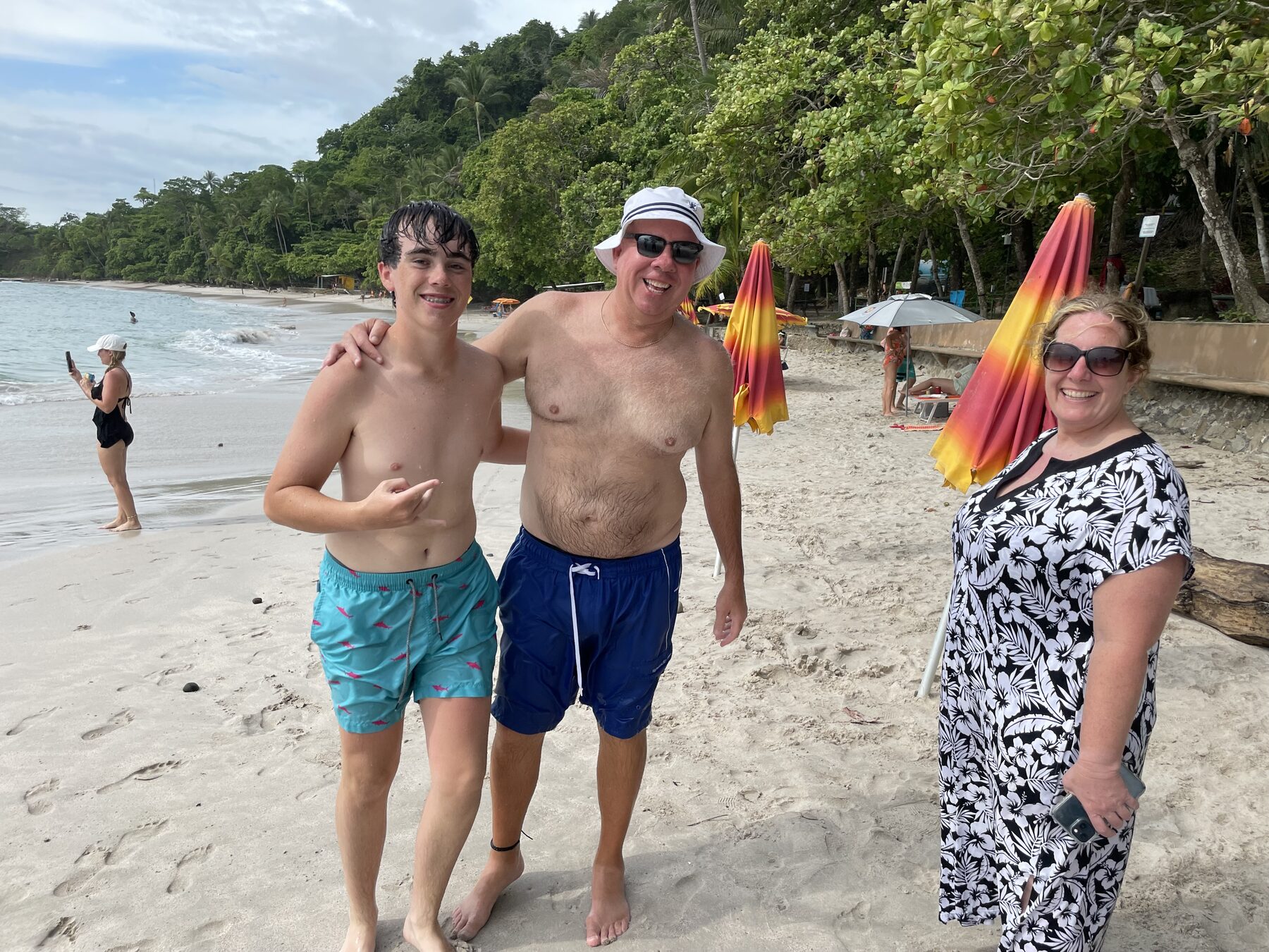 Three guests posing by the beach umbrellas at Playa Mantas — Jaco Costa Rica best snorkeling