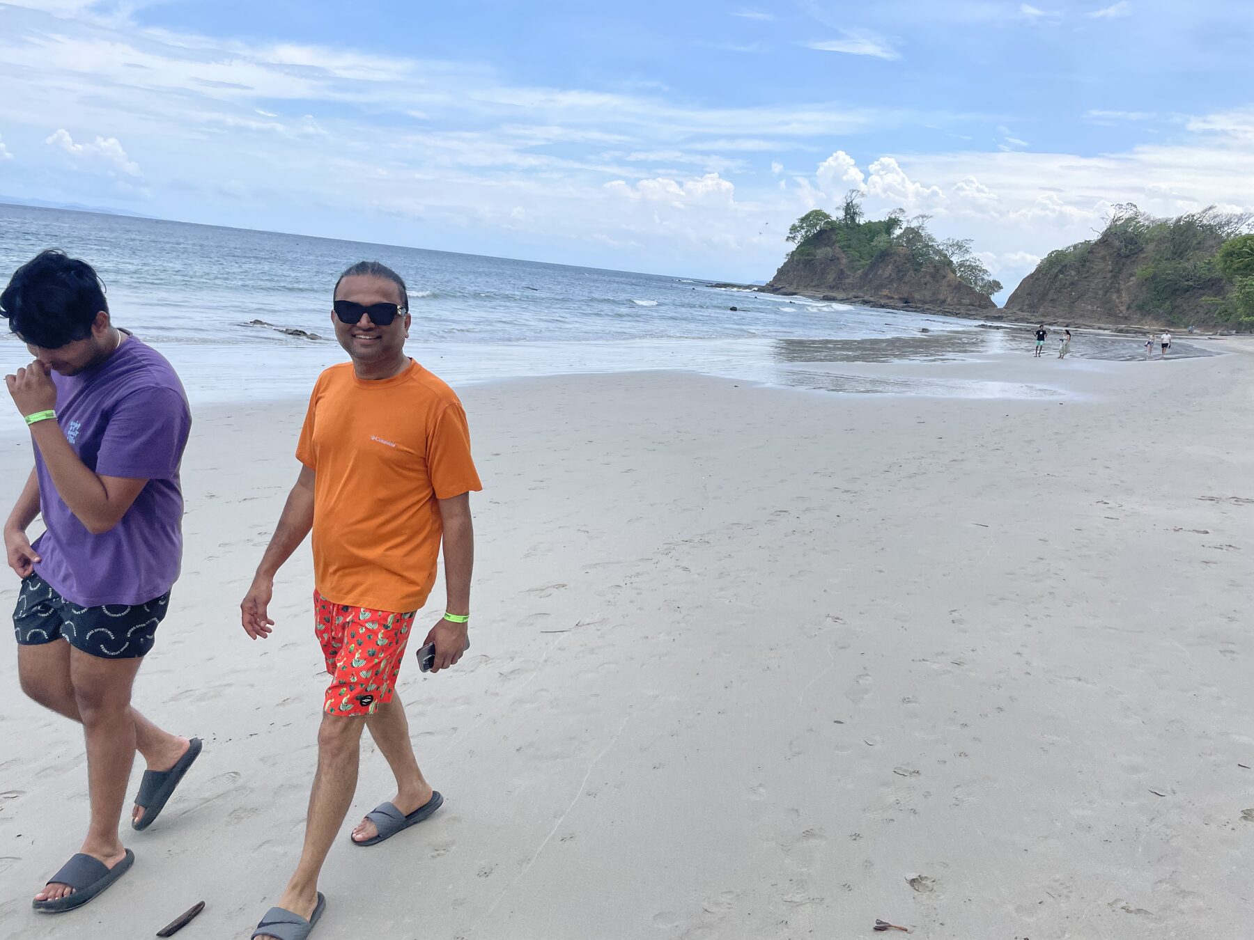 Two guests walking the white sand at Playa Mantas with the headland behind — Jaco Costa Rica best snorkeling