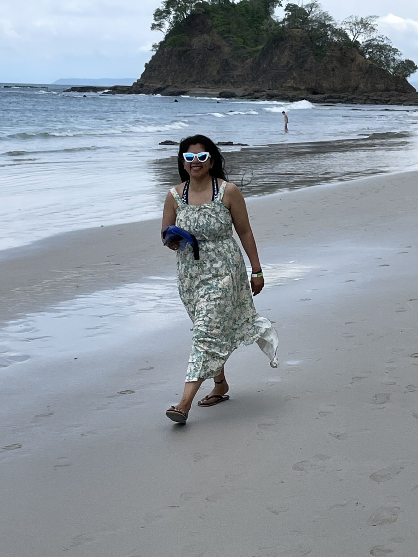 A guest strolling the white sand at Playa Mantas with the headland behind her on a best snorkel tour Jaco beach day